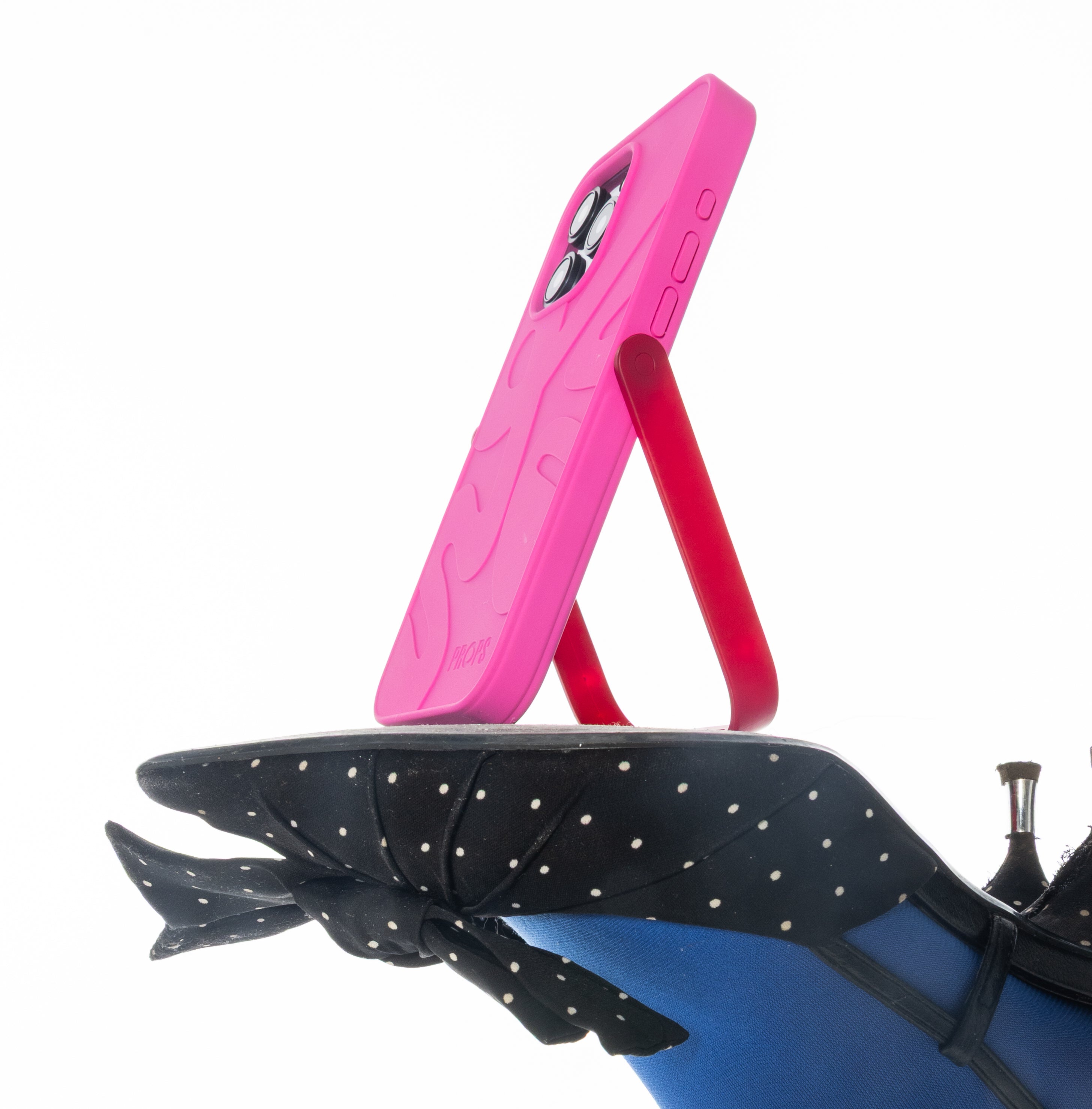 Pink PROPS phone case standing on polka dot heels with a white background