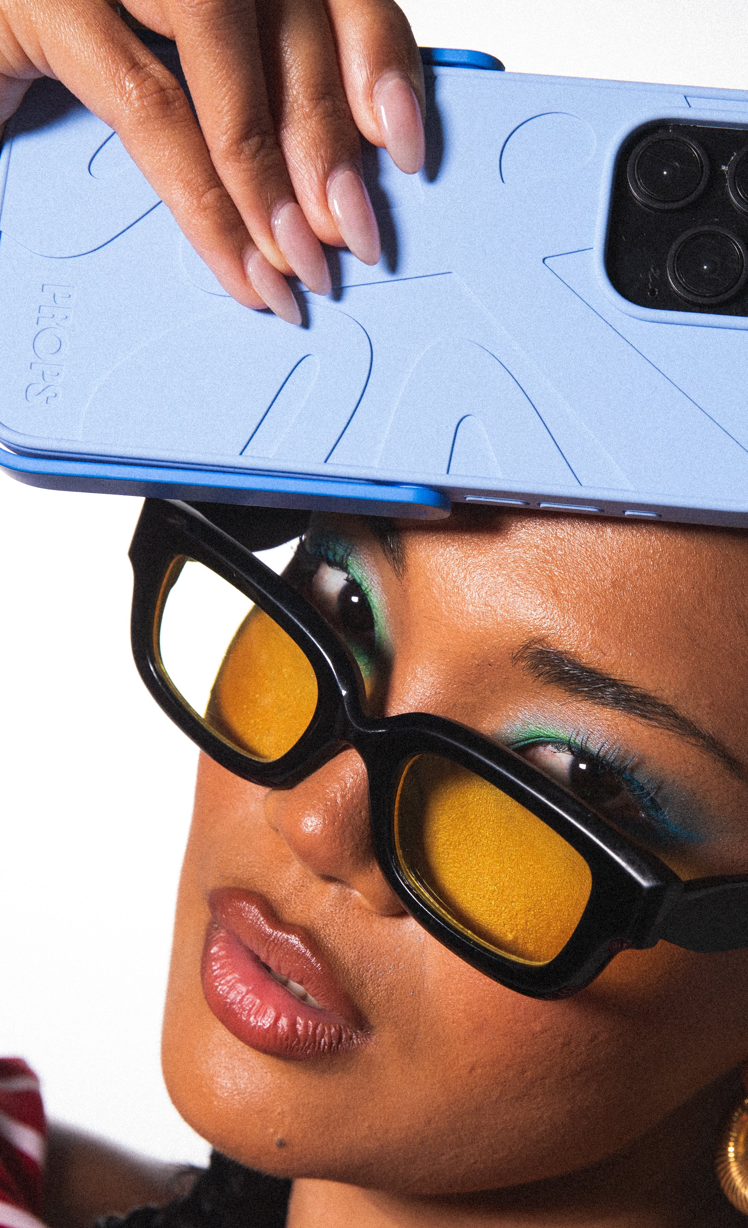 Person wearing sunglasses with a blue PROPS phone case on their head