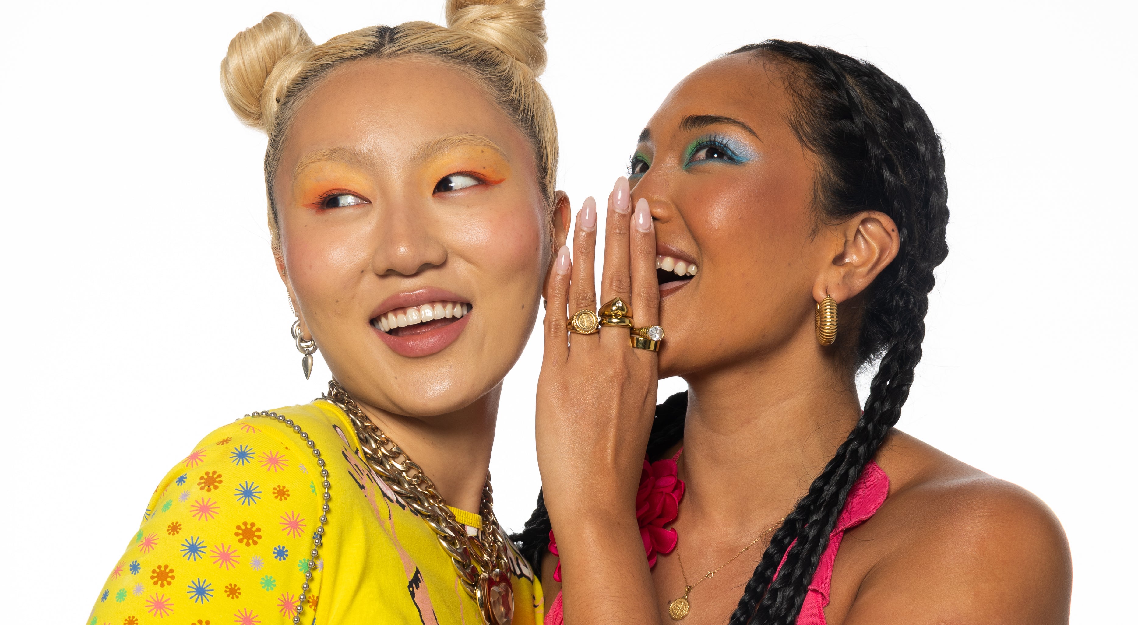 Two women with colorful makeup and hairstyles on a white background