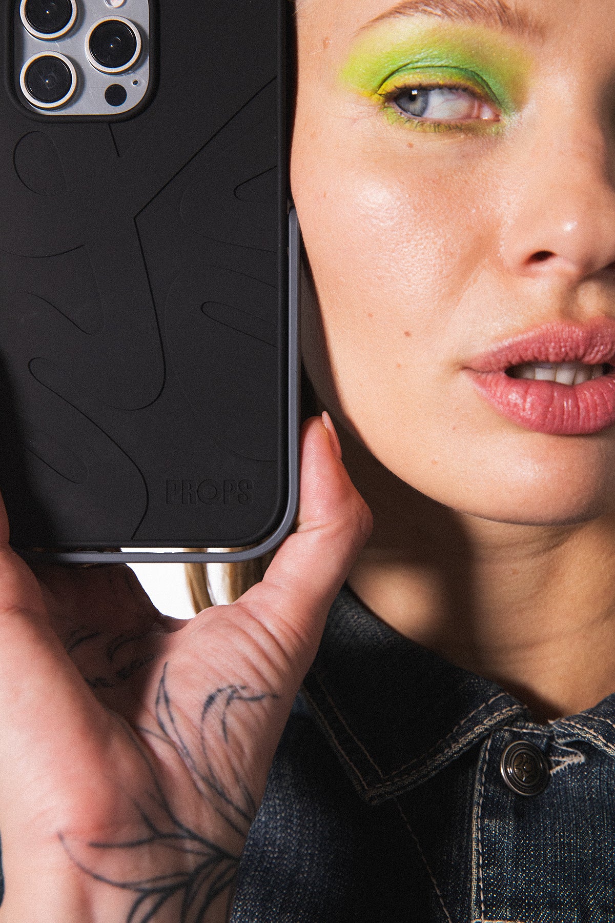 fashion model holds up iphone in a PROPS phone case in studio matte black