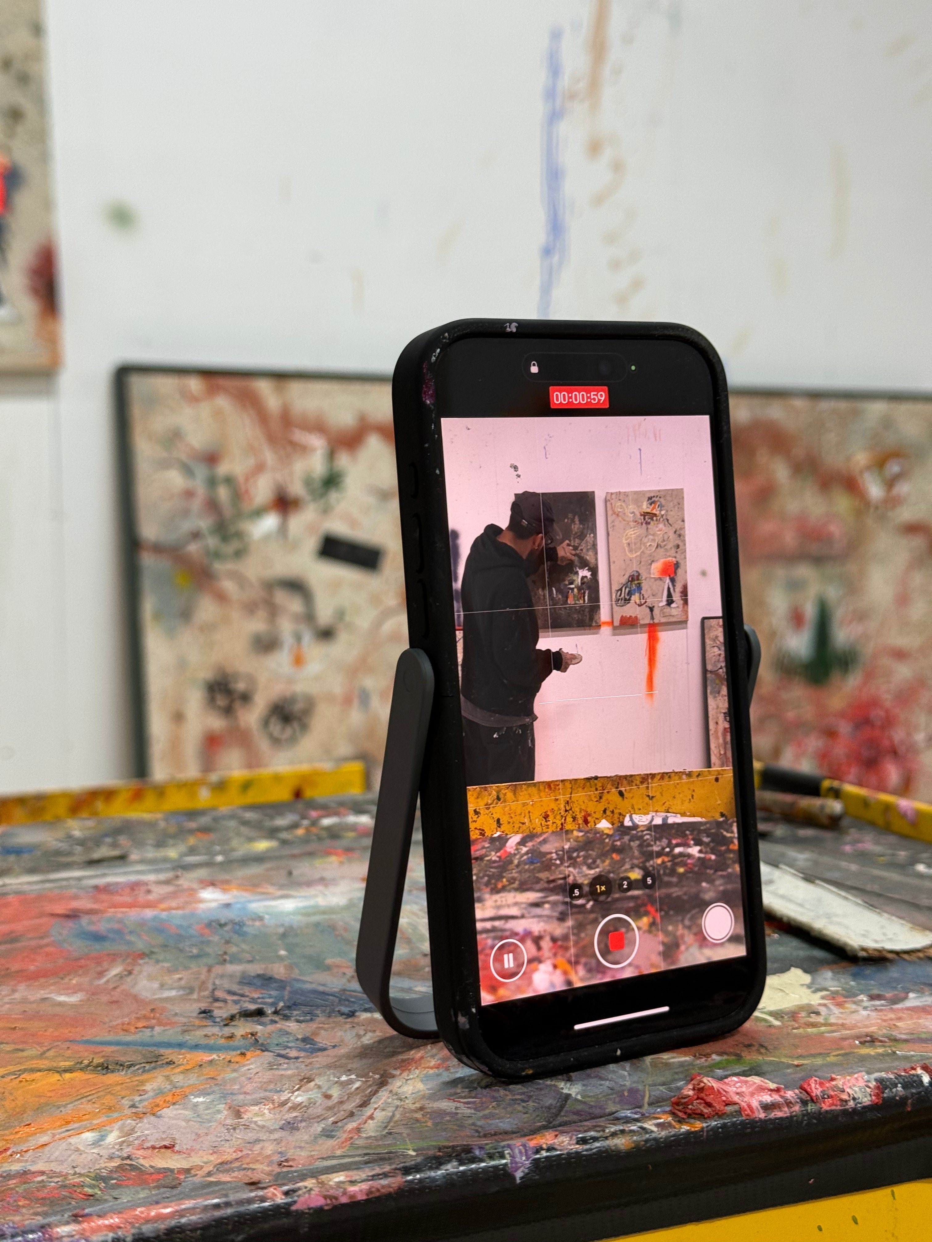 Artist paints canvas, filming his work with iPhone in Props case stand