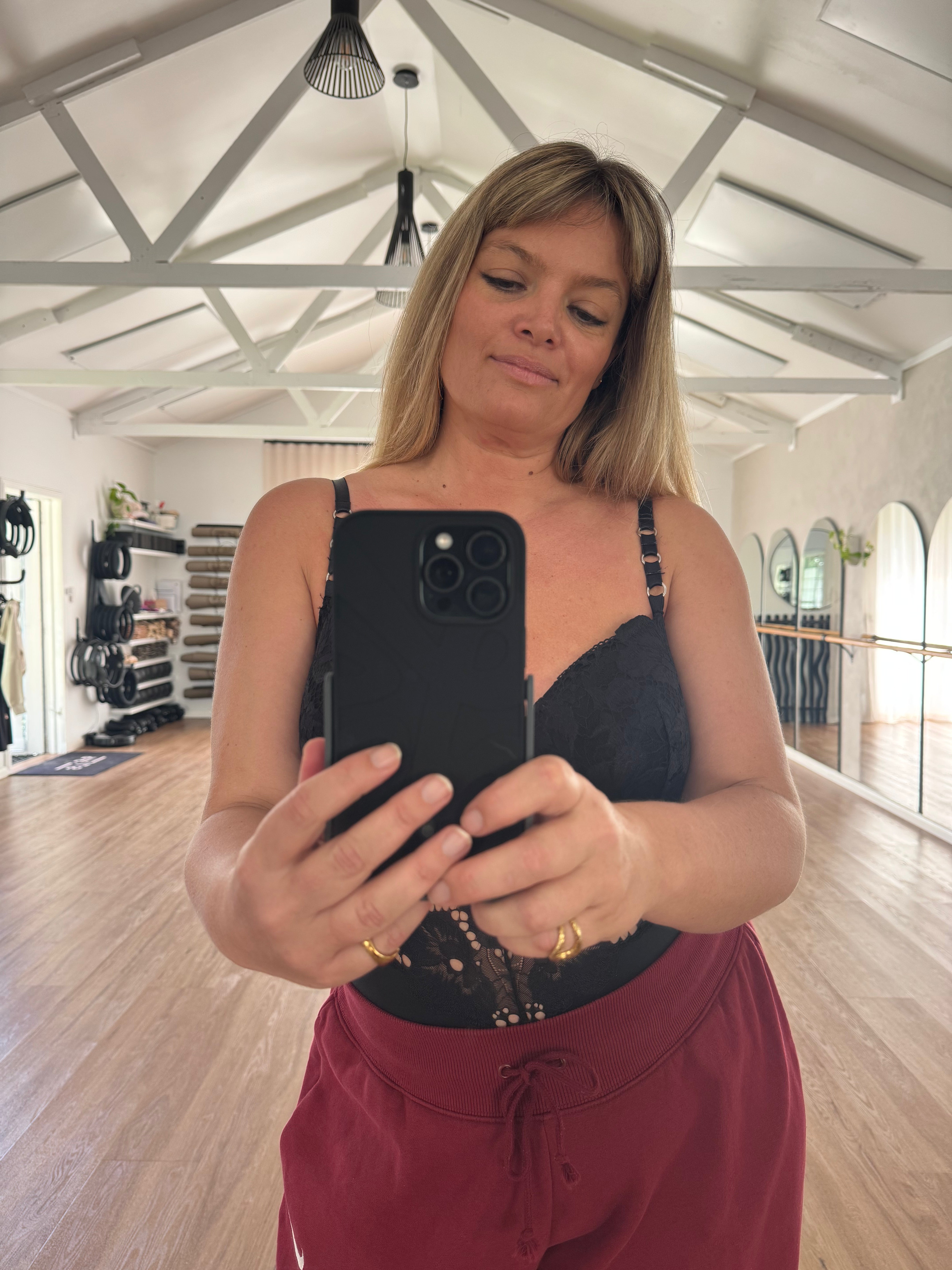 Woman taking a mirror selfie in a dance studio holding a phone in a Props case with stand.