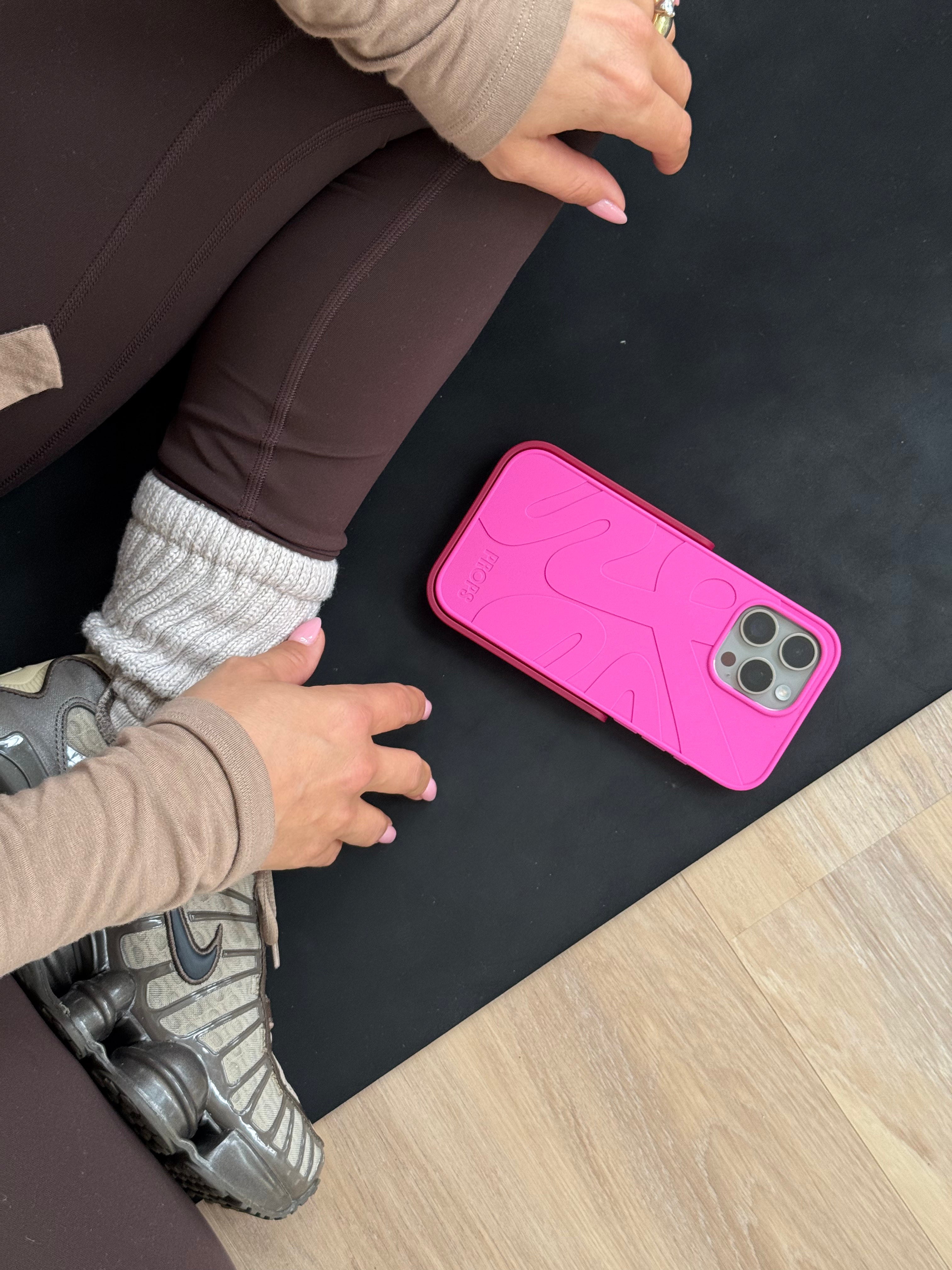 Girl sitting on yoga mat after workout with pink Props phone case